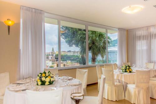 a dining room with white tables and chairs and a large window at Grand Hotel Moon Valley in Vico Equense