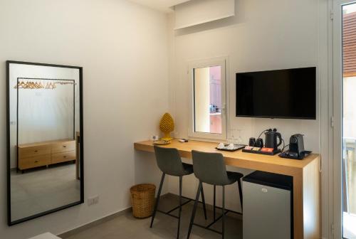 パレルモにあるAl Capo Suite Homeのデスク、椅子2脚、鏡が備わる客室です。