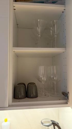 a cupboard with glasses and wine glasses at NesttunPearl in Bergen