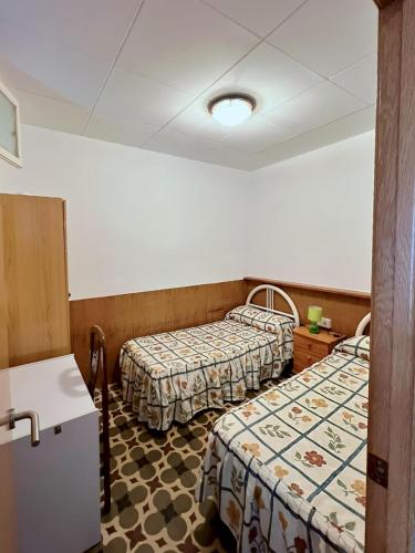 a hotel room with two beds and a refrigerator at La Caseta del Port in L'Ametlla de Mar
