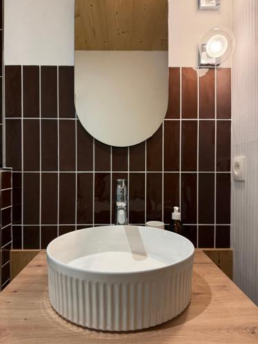 une salle de bain avec un grand lavabo blanc et du carrelage marron dans l'établissement NEW Appartement CŒUR DU VILLAGE, à Praz-sur-Arly