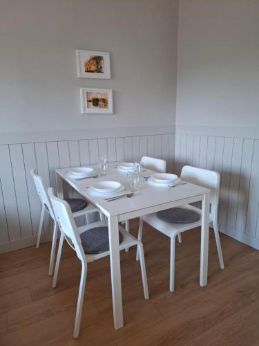 a white dining room table with white chairs at Família Apartmanház in Keszthely