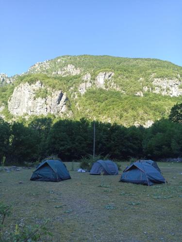 three tents in a field in front of a mountain at North wild camping in Shkodër