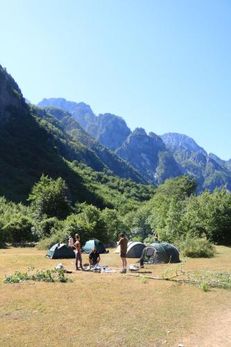 a group of people standing in a field with tents at North wild camping in Shkodër