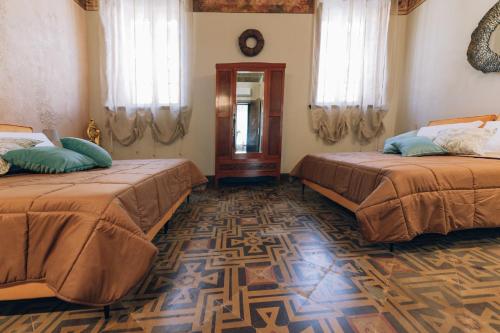 a room with two beds and a mirror at Palazzo Isabella residenza storica in Borgo San Giacomo in Borgo San Giacomo