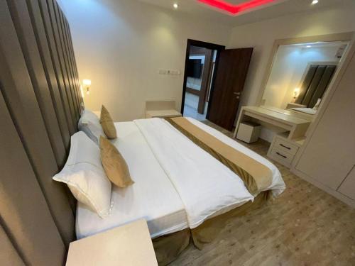 a bedroom with a large white bed with pillows at شقق فخامة المسكن للشقق المخدومة in Al Muzāḩimīyah
