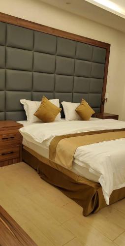 a bedroom with a large bed with a large headboard at شقق فخامة المسكن للشقق المخدومة in Al Muzāḩimīyah