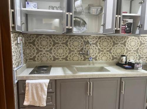a kitchen with white cabinets and a sink at شقق فخامة المسكن للشقق المخدومة in Al Muzāḩimīyah