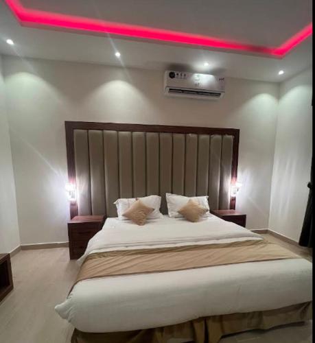 a bedroom with a large bed with a pink light above it at شقق فخامة المسكن للشقق المخدومة in Al Muzāḩimīyah