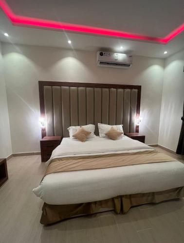 a bedroom with a large bed with a pink light above it at شقق فخامة المسكن للشقق المخدومة in Al Muzāḩimīyah