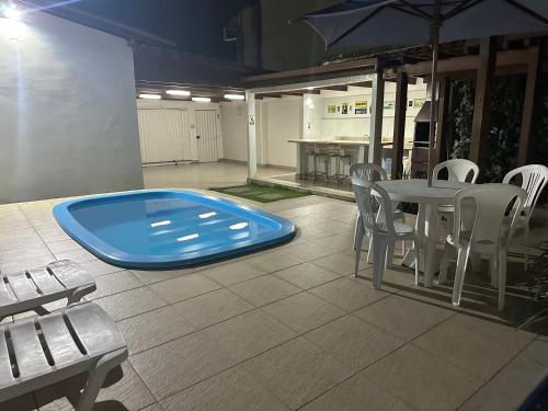 a swimming pool in a room with a table and chairs at Casa da Jana com piscina in Porto Seguro