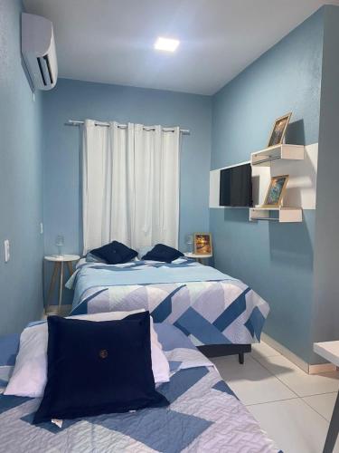 two beds in a bedroom with blue walls at Chale Vista ao Mar Blue in Caucaia
