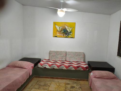 a room with two beds and a chair and a painting at Condomínio em Canoa Quebrada in Aracati