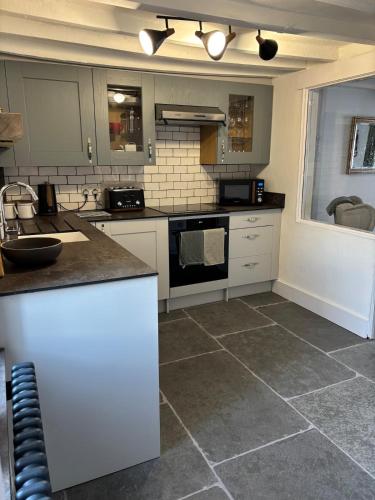 a kitchen with white cabinets and a tile floor at Horseshoe Cottage Edwinstowe in Edwinstowe