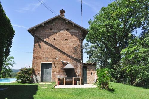 a brick building in the grass next to a pool at Cascina Coccione in Predosa