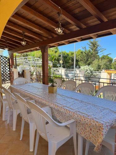 a long table with white chairs and a blue table cloth at Villa Orsa Maggiore - a pochi passi dal mare in Cozze