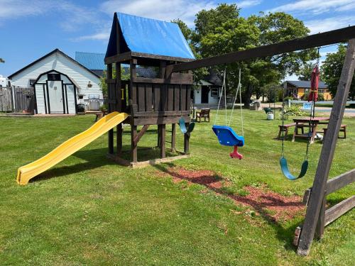 a playground with two swings and a slide at The Coastal Cabins in New Brunswick in Cape Tormentine