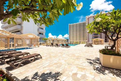 a patio with benches and trees and buildings at Ocean & Diamond Head View Studio at Waikiki in Honolulu