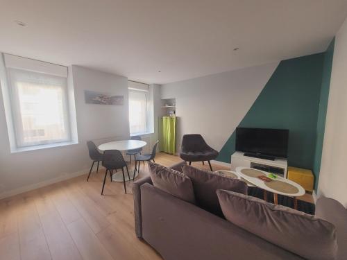 a living room with a couch and a table and chairs at Appart 2 chambres *Notre bout du monde* in Brest