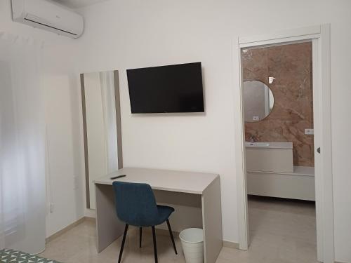 a white room with a desk and a tv on a wall at Le stanze di Anna in Grottole