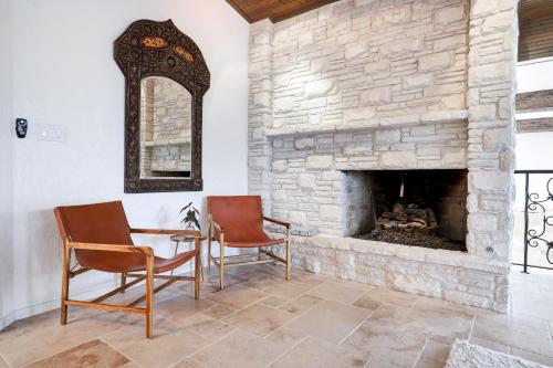a room with two chairs and a stone fireplace at Majestic Oak - Luxury, Billiards Room & Pool in San Antonio