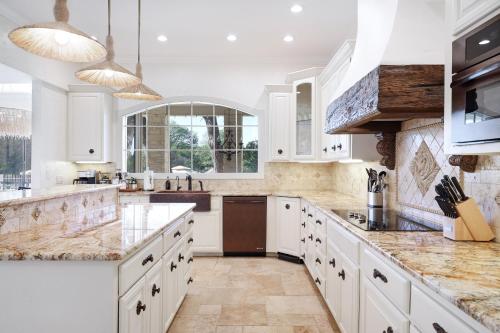 a large kitchen with white cabinets and marble counter tops at Majestic Oak - Luxury, Billiards Room & Pool in San Antonio