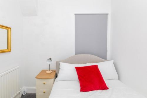 a red pillow sitting on top of a white bed at Charming 2-bedroom house in Hartlepool