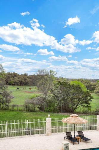 a patio with two chairs and an umbrella and a fence at Majestic Oak - Luxury, Billiards Room & Pool in San Antonio