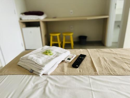 a pile of towels and a remote control on a bed at Pousada Solar de Penha in Penha