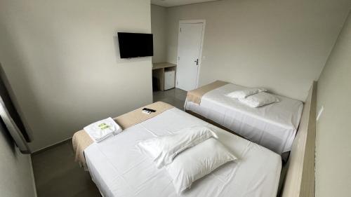 a hotel room with two beds and a television at Pousada Solar de Penha in Penha