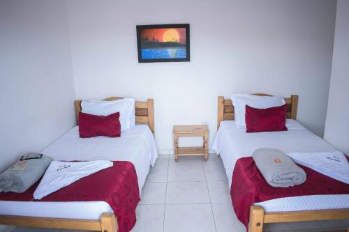 a bedroom with two twin beds with red pillows at Hotel Majestic plaza in Mompós