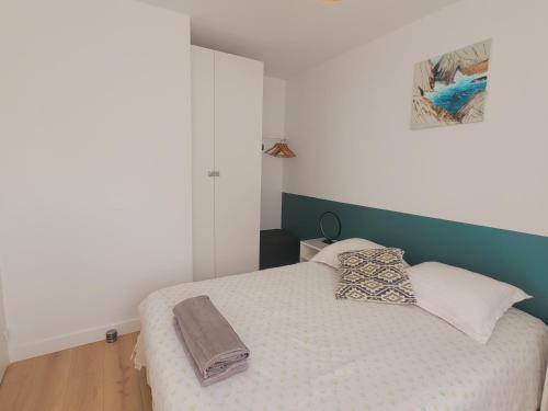 a bedroom with a white bed with a green headboard at Appart 2 chambres *Notre bout du monde* in Brest