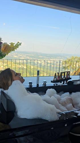 una donna sdraiata in una vasca da bagno piena di neve di Refúgio Muas Nature a Vila Real