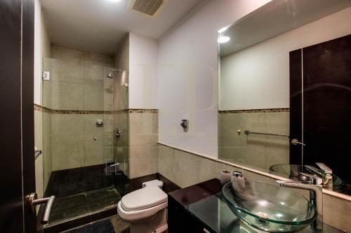 a bathroom with a toilet and a glass sink at CR MARIPOSA RENTALS lakeview, spacious penthouse with office, pool, gym, Jacuzzi in Santa Ana