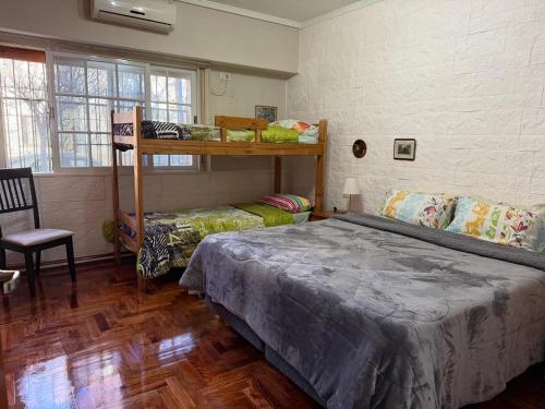 a bedroom with two bunk beds and a chair at Chalet Buenos Aires in Buenos Aires