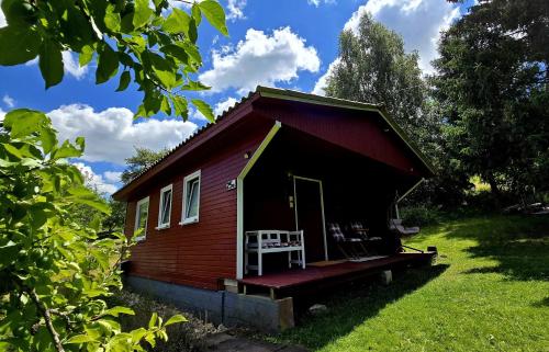 a small red house with a white chair on the porch at gemütliches TinyHouse im Naturpark in Rorodt