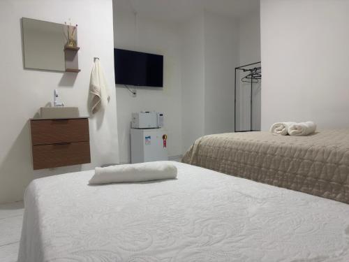 a bedroom with two beds and a tv and a dresser at Abaíra Serra Azul Lofts 1 in Petrolina