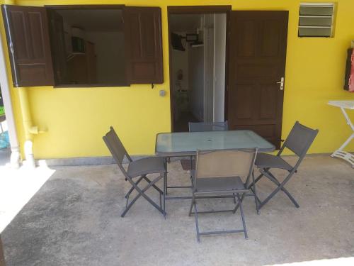 a table and chairs in front of a yellow wall at Au Petit Canal Fleuri in Rémiré