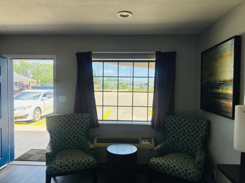 a living room with two chairs and a table and a window at Executive Inn & Suites West Columbia in West Columbia