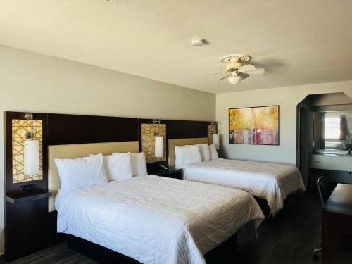 a bedroom with two beds with white sheets at Executive Inn & Suites West Columbia in West Columbia