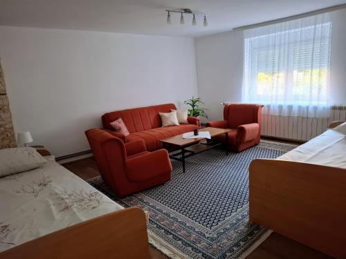 a living room with two red chairs and a couch at Home Well Apartman Vranje in Vranje