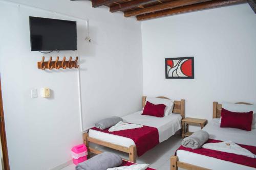 a room with two beds and a tv on the wall at Hotel Majestic plaza in Mompós