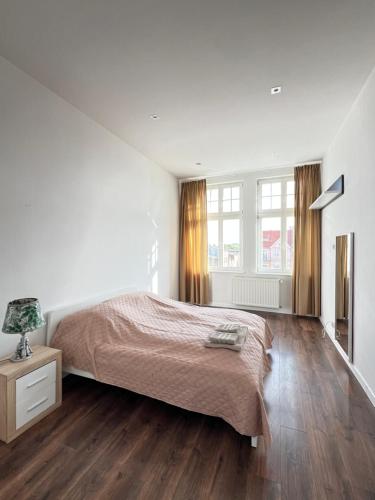 a bedroom with white walls and a bed and wooden floors at Long Island in Grudziądz