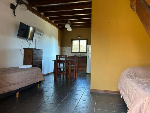 a room with a bedroom with a table and a kitchen at Barranca Del Indio in Merlo