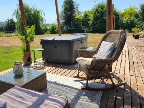 a patio with a hot tub and two chairs and a table at The Riverside Retreat in Blakeney