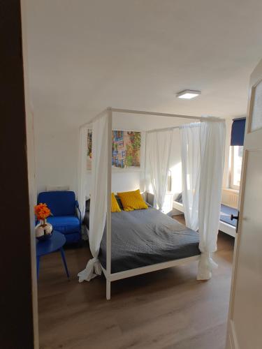 a bedroom with a canopy bed and a blue chair at Eastern in Tilburg