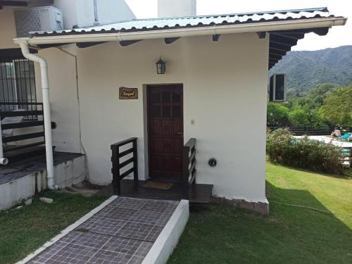 a white house with a brown door and a staircase at Cabañas Noscohue in Villa General Belgrano