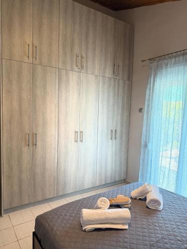 a bedroom with a bed with towels and cabinets at Serenity home Salamina in Áyios Yeóryios