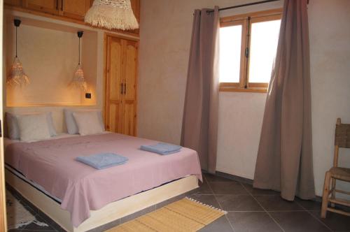 a bedroom with a bed with pink sheets and a window at Villa Labri de la Plage 350 m from Beach & Center in Sidi Kaouki
