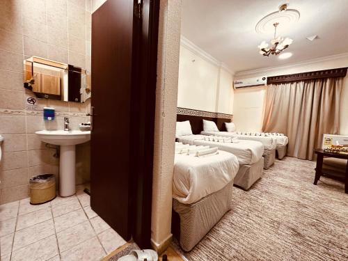 a hotel room with a row of beds and a sink at ارجوان الصفوة بلازا - arjuan alsafwa in Miná